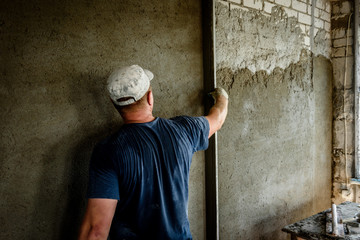Obraz na płótnie Canvas Construction worker plastering wall with leveler.