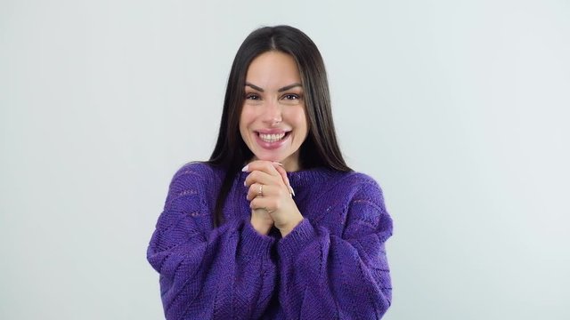 Surprised excited happy young woman claps hands over white wall background.