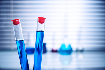 Two test tubes with blue liquid in the laboratory on the background of glass flasks.
