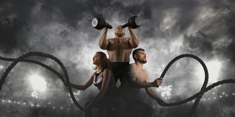 Sporty woman and man working out with battle ropes. Sports banner