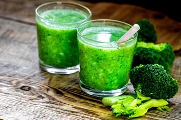 Green vegetable smoothie in glass at wooden background