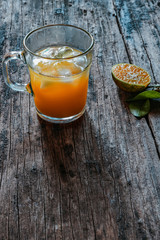 A glass of orange juice on a vintage wooden table, complemented by slices of fresh local oranges and their leaves. In Indonesia this drink is called jus jeruk.
