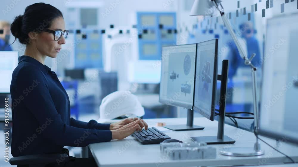 Poster Beautiful Female Engineer Working on Personal Computer in the High-Tech Industrial Factory, She Uses CAD Software to Model Heavy Industry High Tech Mechanism 3D Model. Side View Portrait 
