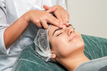Fototapeta na wymiar Beautiful young woman receiving face massage at beauty salon, close up.