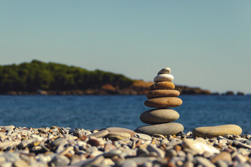 Pyramid of stones on the beach. Stack of stones against blurred seascape, space for text. Zen concept