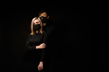 An Asian man hugs a European girl. They are wearing medical masks. Virus, bad ecology. Coronavirus...