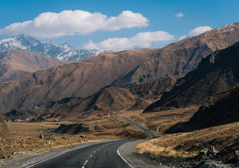 scenery. view of the highway stretching into the dark gray mountains in the distance covered with snow