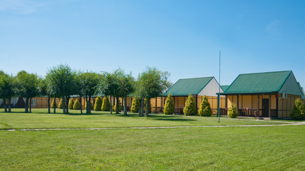 small houses with green roofs stand in a row near the green lawn under the clear summer sky