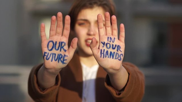 Climatic strike. Close portrait of a short-haired girl. The student holds her hands in front of her, the inscription on them - our future is in your hands