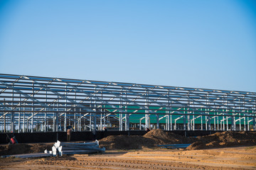 Steel frame workshop is under construction against a blue sky