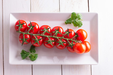 a branch of small cherry tomatoes on top of a table