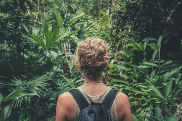 young woman with backpack hiking in tropical jungle / rainforest