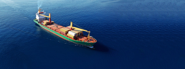 Fototapeta premium Aerial drone top down photo of industrial cargo container carrier docked in commercial port terminal