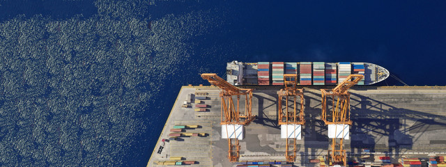 Aerial drone top down photo of industrial cargo container carrier docked in commercial port terminal