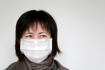 Woman in medical mask and scarf wrapped around the throat on white background. Concept of illness, fever, coronavirus symptoms, cold and flu