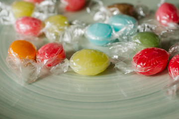 Heap of colorful candies of different flavors on blue background, close up view. 