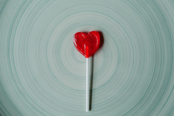 Heart shaped lollipop on blue background. 