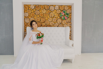 Beautiful happy bride in a room with a wedding bouquet.