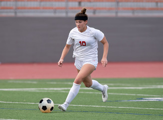 Young athletic girl playing soccer in a game