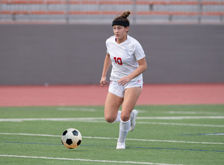 Fototapeta premium Young athletic girl playing soccer in a game