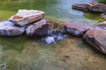 Fototapeta premium Beautiful view of pond decorated with big rocks. Clear water mirror surface effect.