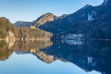 Fototapeta na wymiar Stunning view of the Alpsee lake in winter on a sunny day with the Neuschwanstein Castle, Hohenschwangau Castle and Bavaria Alps in background, with beautiful reflections in water, Bavaria, Germany