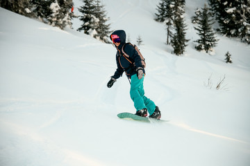 Female snowboarder riding down the mountain snowcovered slope