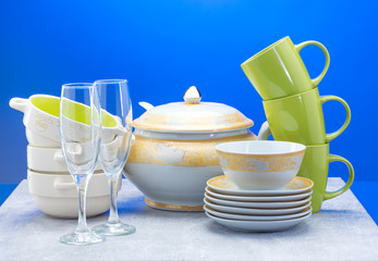 Clean plates, glasses, cups and cutlery on blue background