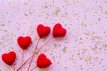Five red toy hearts on pink festive background with golden confetti. Valentines day concept. Top...
