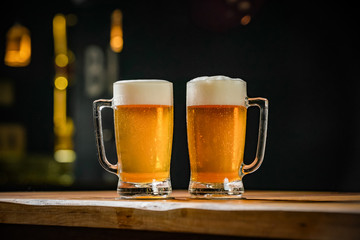 Two mugs full of chopp, one with pilsen chopp and one with dark chop on a rustic table