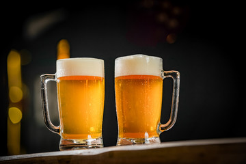 Two mugs full of chopp, one with pilsen chopp and one with dark chop on a rustic table