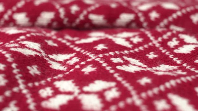 Dolly shot rotating shot of soft warm knitted red and white Christmas woolen fabric. Rotated macro shot of fluffy winter design wool textile, cloth, blanket. Knitwear. Shot in 6k.