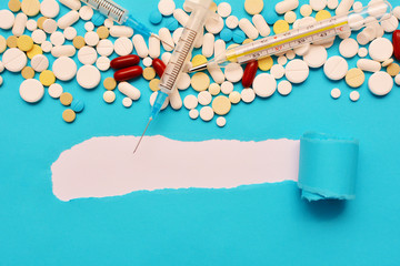 Medications for the treatment of coronavirus, seasonal viral and influenza infections. Thermometer, tablets, syringe in the blue background. Place for text, flat lay, mock up.