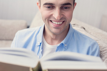 Young guy reading a book, man sitting at home, portrait, close up, toned