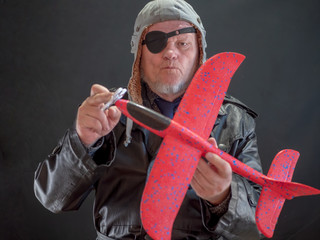 portrait of a bizarre elderly man has in his hands red airplane and propeller spinner torque. fancy...