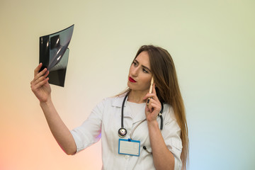 Pensive young doctor examining x-ray and making diagnosis. Medical concept
