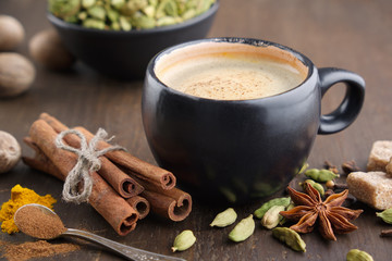 Cup of coffee with spices. Cinnamon sticks, cardamom, allspices, curcuma and anise on wooden table.
