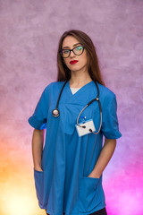 Attractive woman in medical uniform posing on abstract background. Woman doctor or nurse