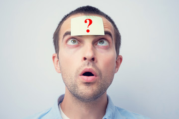 Amazed man with sticker with a question mark. The concept of thinking, portrait