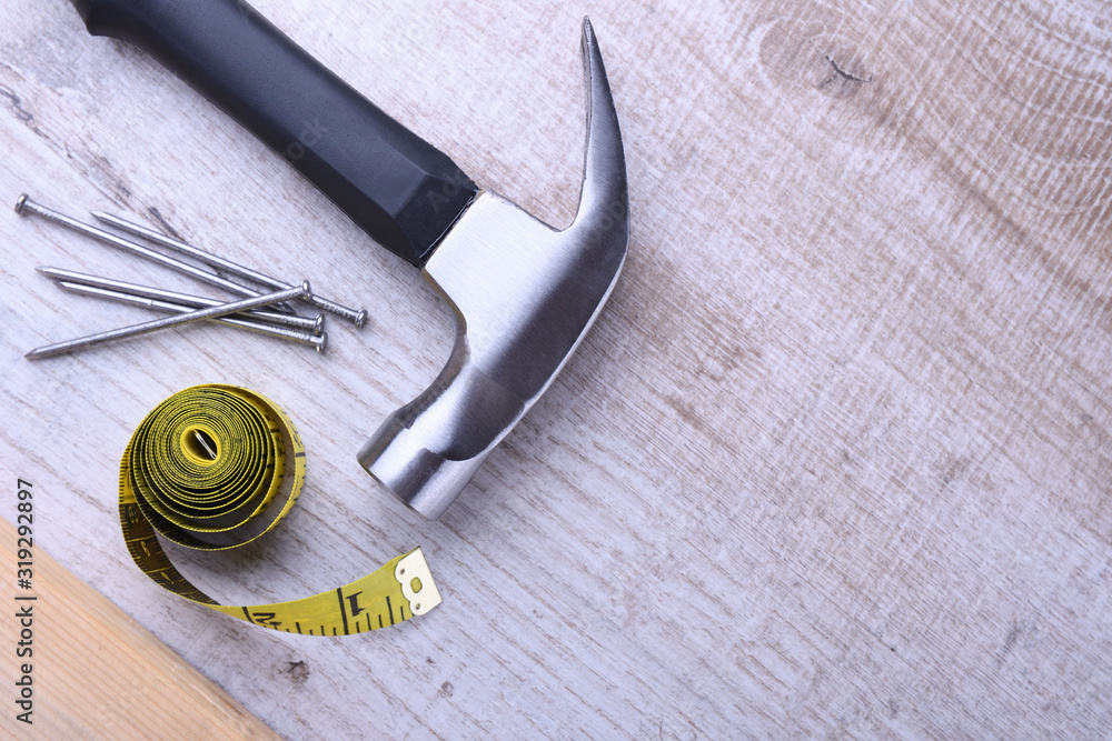 Poster Hammer iron,centimeter tape and nails on wooden background