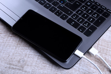 Plug in USB cord,cable charger,charging,charged and data transfer of the mobile phone,smartphone with a laptop on wooden floor,table Top view