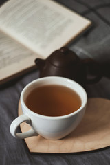 Cup of tean and teapot on wooden heart book and scarf on background