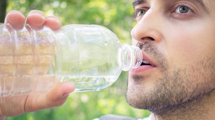 Person with bottle water, man quenches thirst, closeup, toned, 16:9