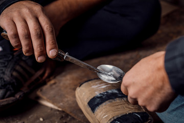two shabby  men preparing drug injection in slums