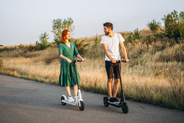 Young couple on vacation having fun driving electric scooter on the road in the countryside. Content technologies. Copy space