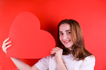 The concept of Valentine's Day or Women's Day. Young girl with a big red heart in her hands. Copy space. Picture frame