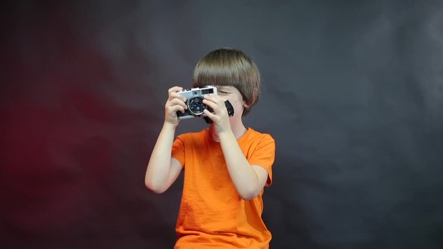Child photographer with a sealed mouth looks the peephole of the camera.