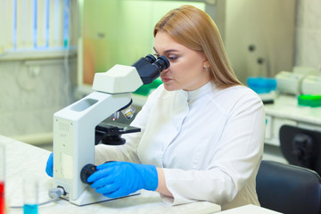 Naklejka na ściany i meble Laboratory assistant working with a microscope in a scientific laboratory.