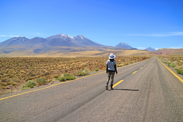 Female Traveler walking on the empty road of Atacama desert in northern Chile