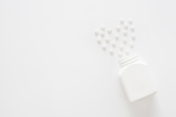 White tablets on a white background, laid out in the shape of a heart, with copy space. The concept of the medicines and pills. 